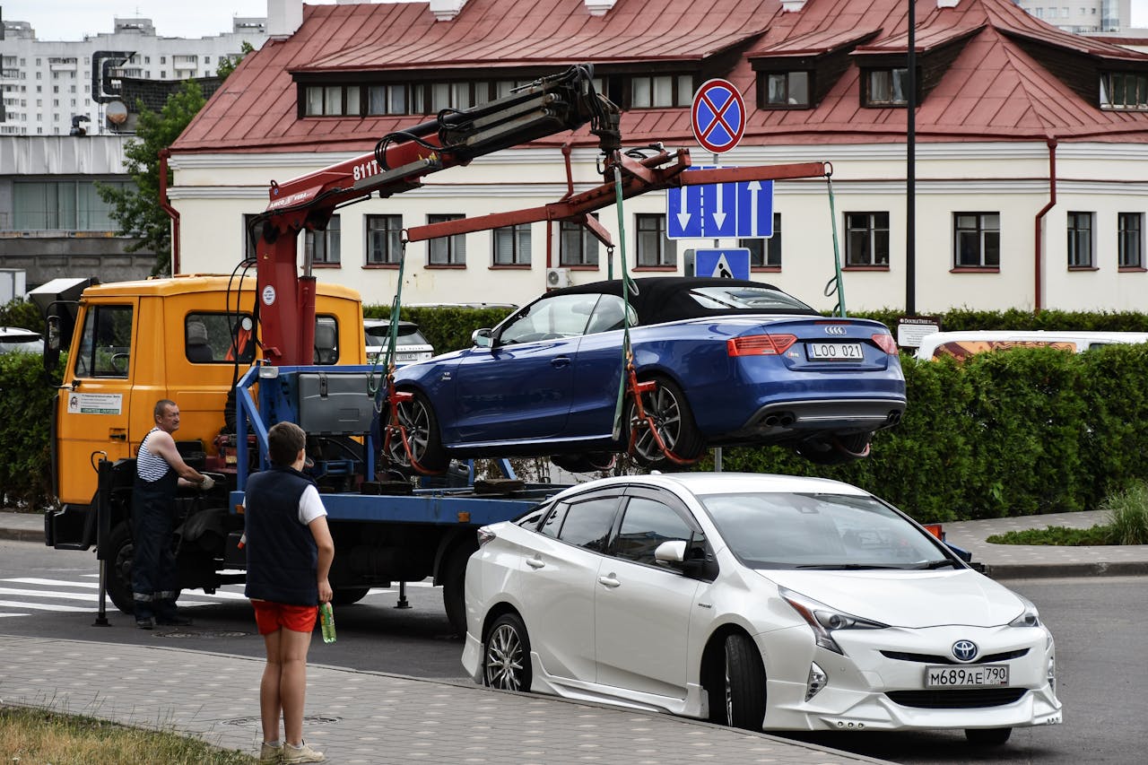 programs-01 Towing a blue Audi convertible in a bustling city street.
